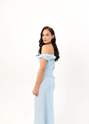 Woman wearing a light blue off-shoulder linen dress on a white background