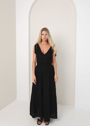 Woman wearing a black dress standing in a minimalistic setting with an archway.