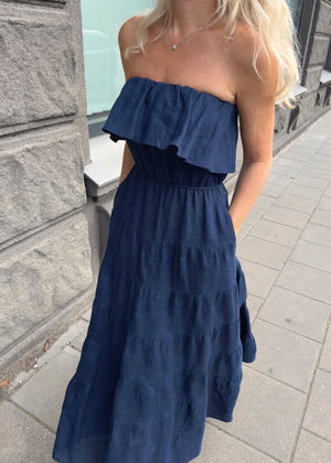 Woman wearing a Bohomey navy blue strapless linen dress on a sidewalk.