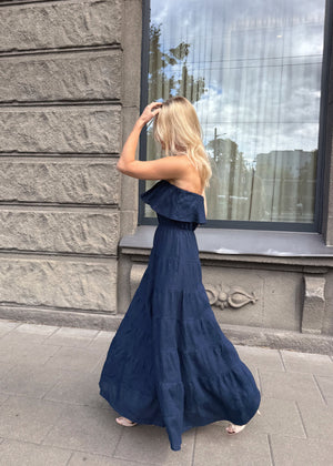 Woman in a Bohomey long navy blue strapless maxi linen dress standing in front of a stone building with large windows.