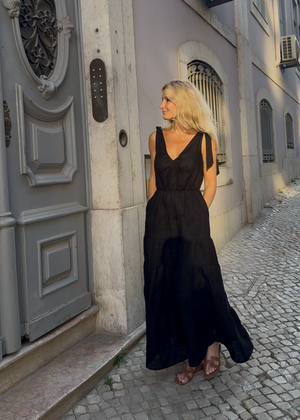 Woman in a Bohomey black linen maxi dress standing on a cobblestone street with a building in the background