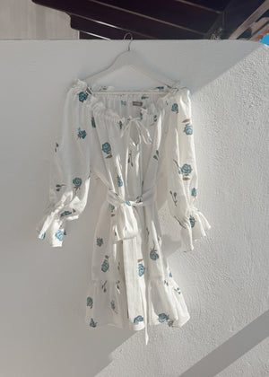 Bohomey white linen dress with blue floral pattern hanging on a white wall