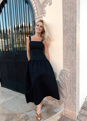 Woman in a Bohomey black linen dress standing in front of an ornate building entrance.