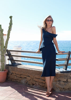 Woman in a Bohomey linen navy blue dress standing by a railing with a scenic ocean view.