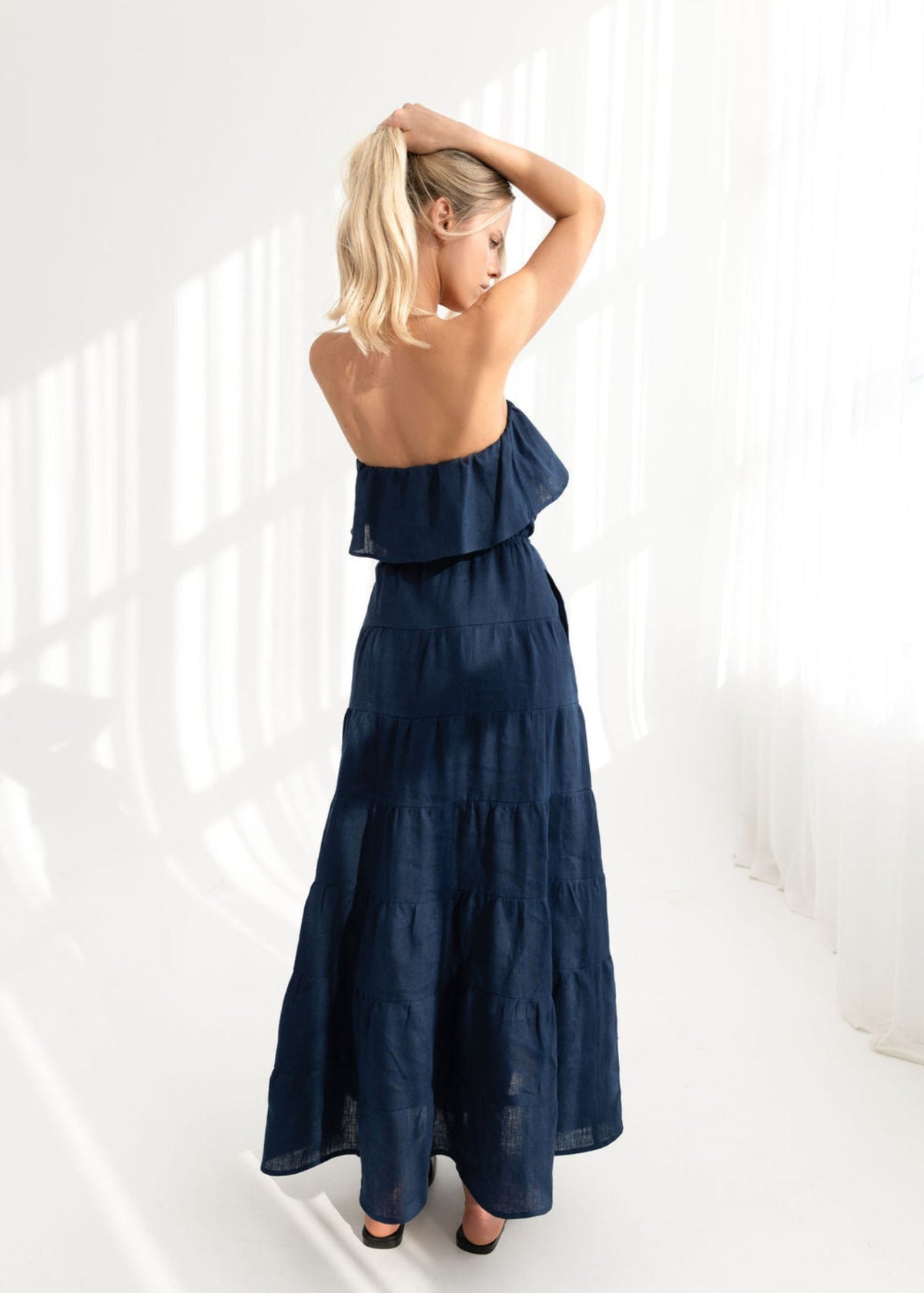 Woman wearing a navy blue strapless dress against a white background