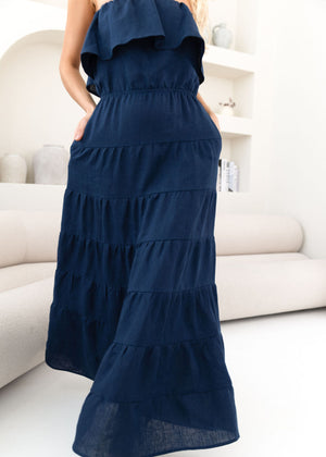 Navy blue tiered dress worn by a person in a minimalistic room.