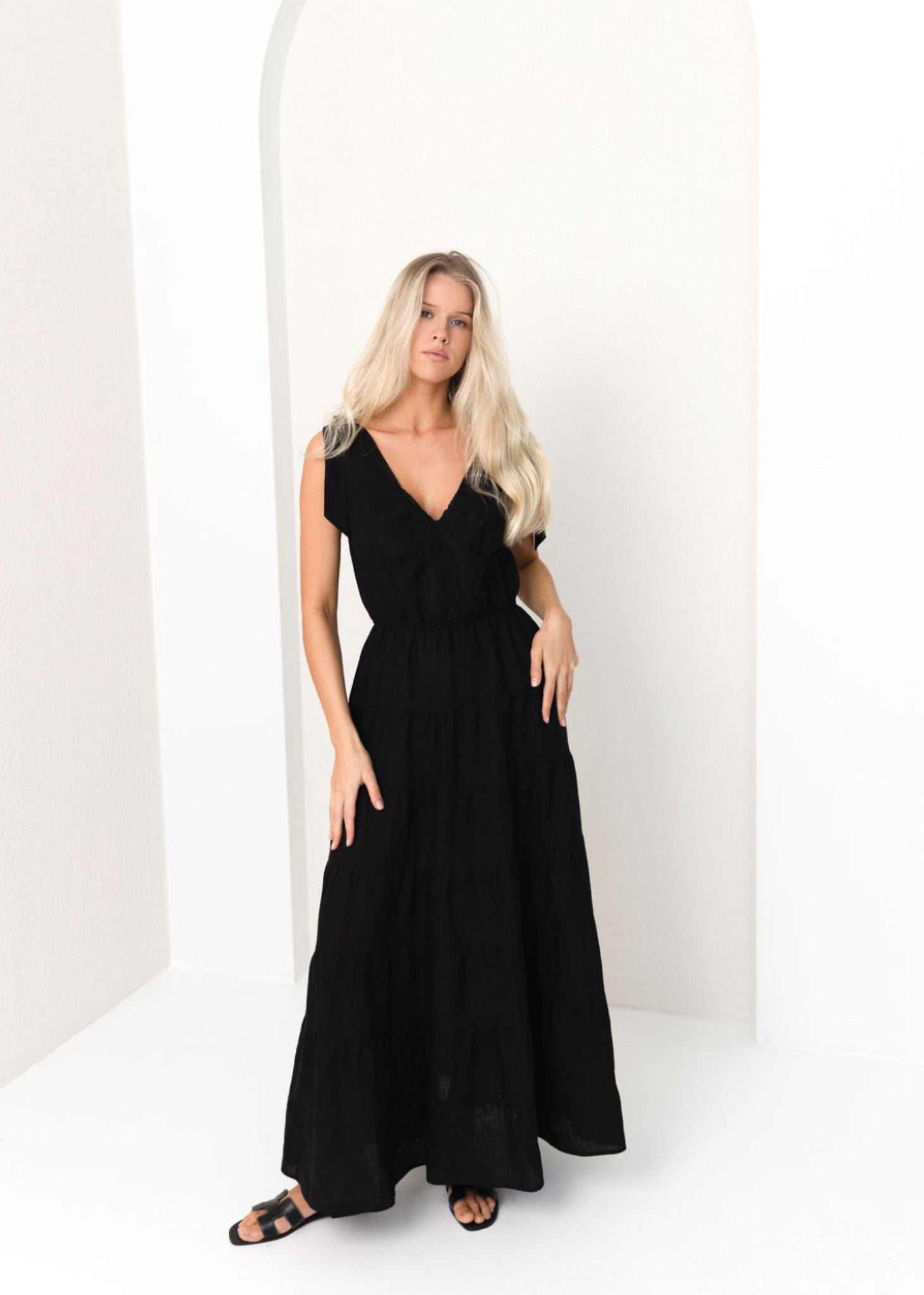 Woman wearing a black linen dress in a white studio setting