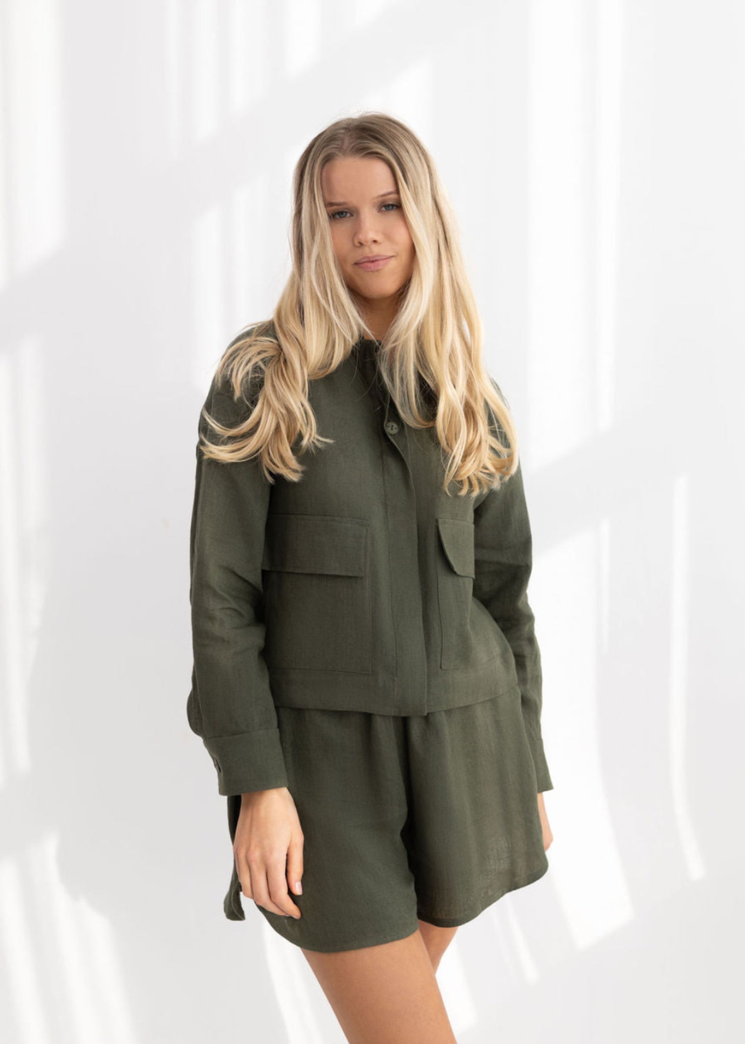 Woman wearing a green jacket and skirt set on a white background