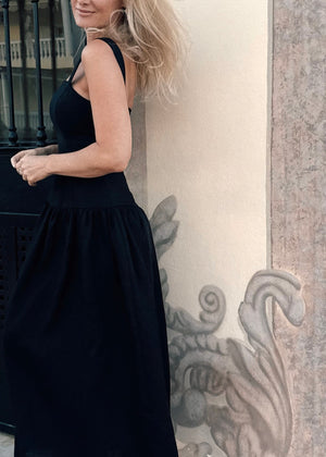 Woman wearing Bohomey black linen dress standing against a decorative wall.